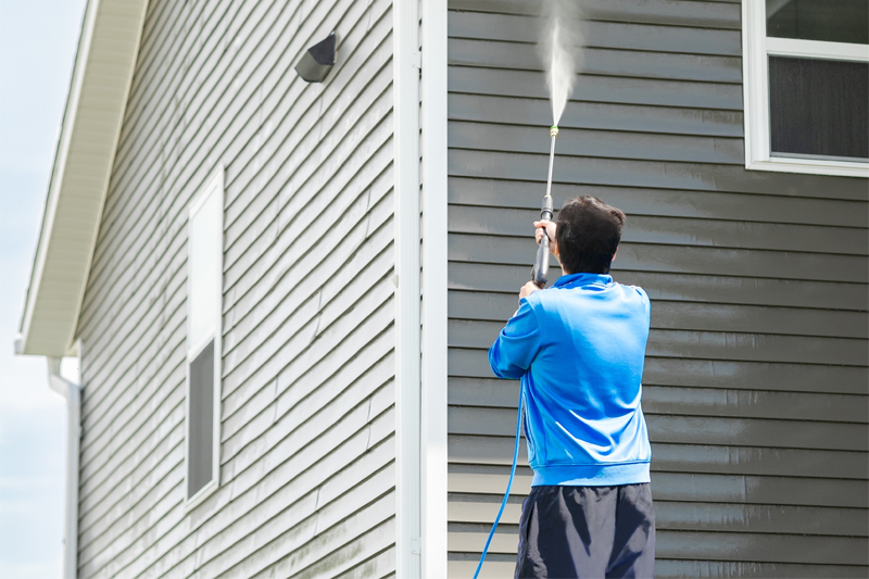 A Transcend Roofing Company representative spraying a house with a hose.