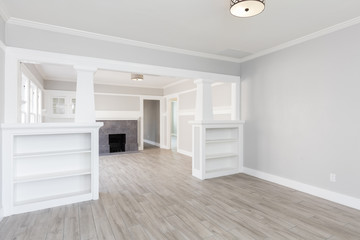 Empty living room with hardwood floors and white walls, transformed by Transcend Roofing Company.