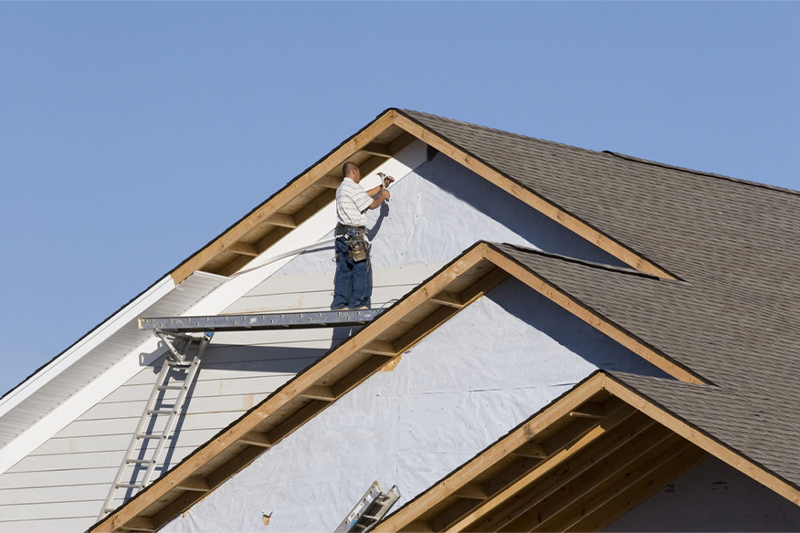 A man is working on the roof of a house for Transcend Roofing Company.
