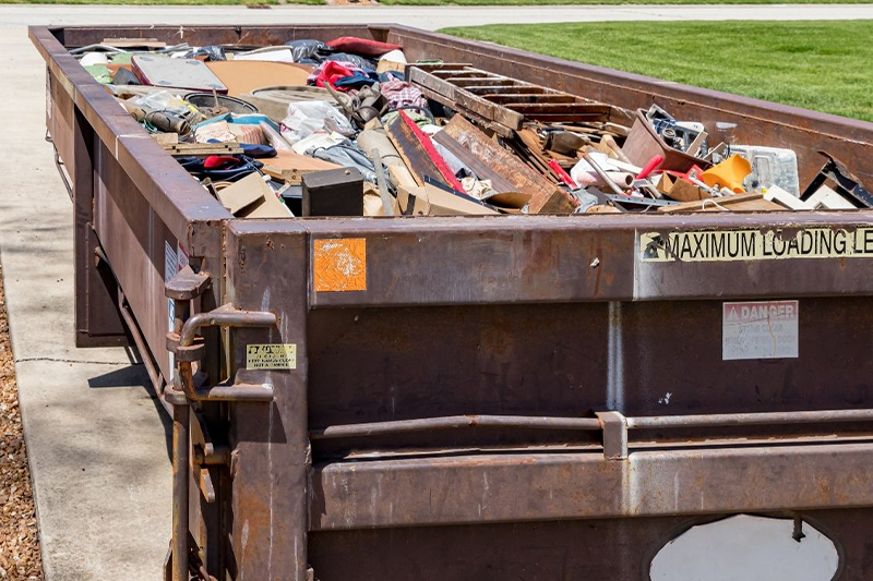 A dumpster filled with junk utilized by Transcend Roofing Company.