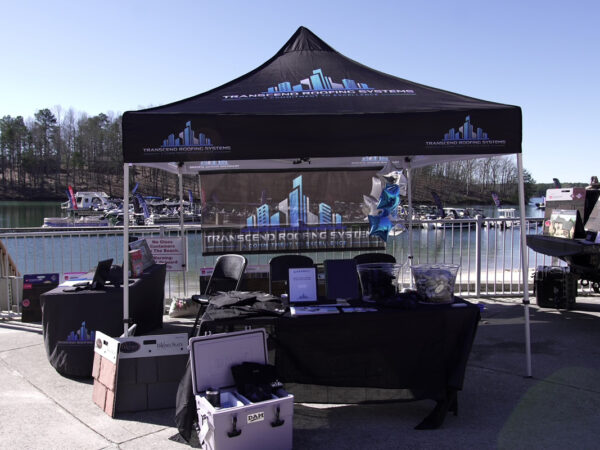 A Transcend Roofing Company tent is set up near a lake. A Transcend Roofing Company tent is set up near a lake.