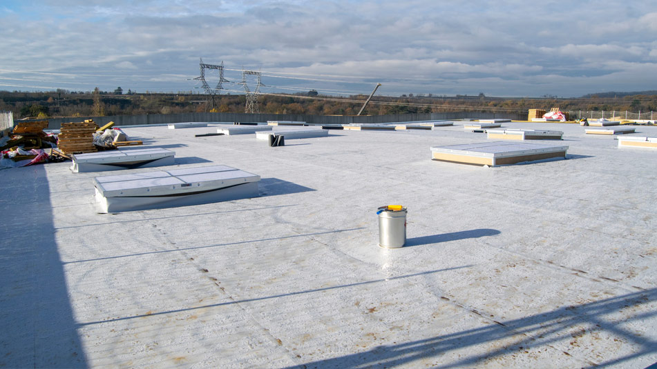 A flat roof with various construction materials and roof hatches scattered around, under a partly cloudy sky with distant power lines visible, highlights the meticulous work involved in professional roofing services. A flat roof with various construction materials and roof hatches scattered around, under a partly cloudy sky with distant power lines visible, highlights the meticulous work involved in professional roofing services