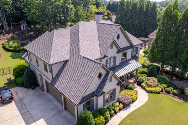 Aerial view of a two-story suburban house with a well-maintained yard, surrounding trees, a driveway, and a parked car. Aerial view of a two-story suburban house with a well-maintained yard, surrounding trees, a driveway, and a parked car.